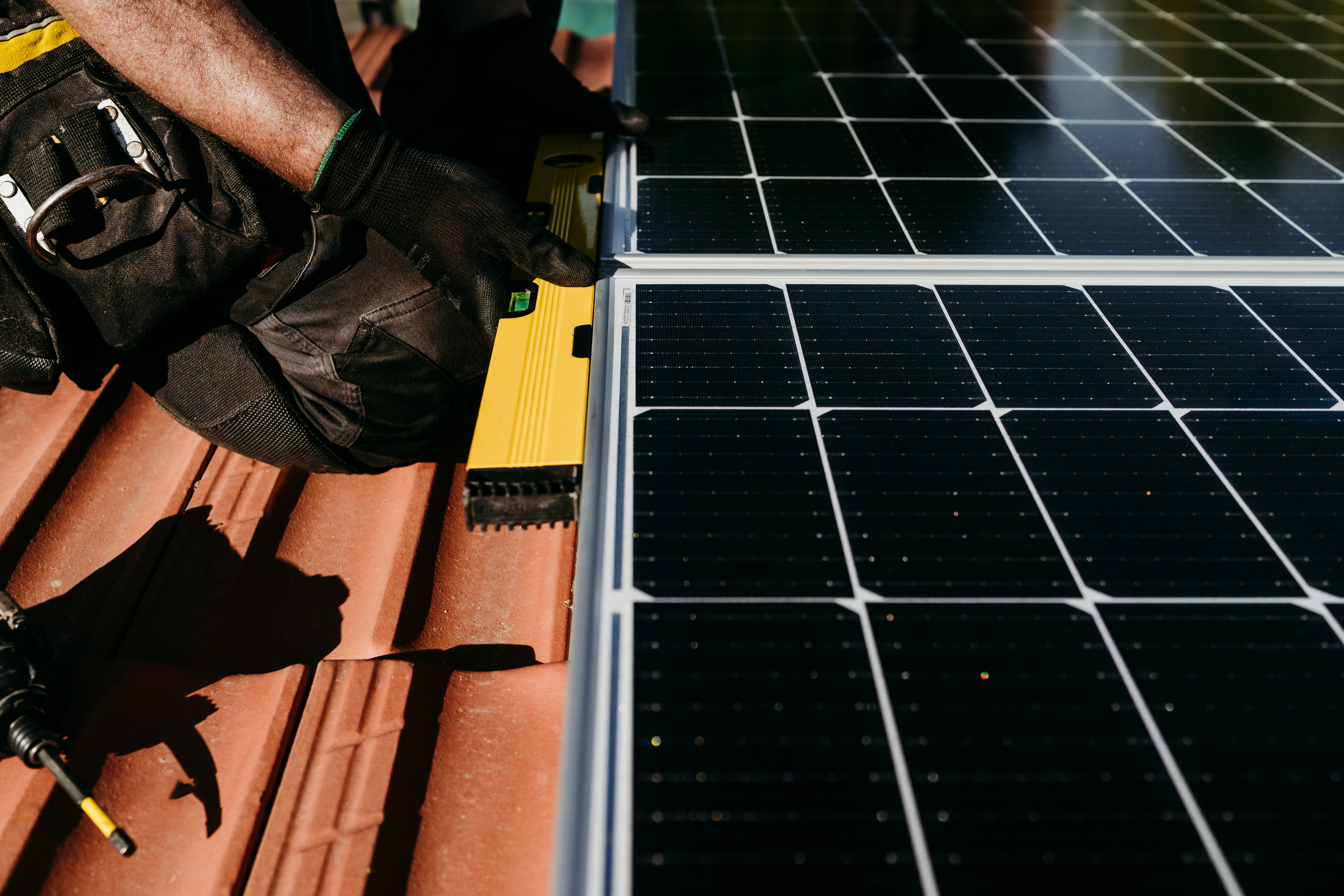 Technician man using level on solar panels on house roof for self consumption energy.Renewable energ